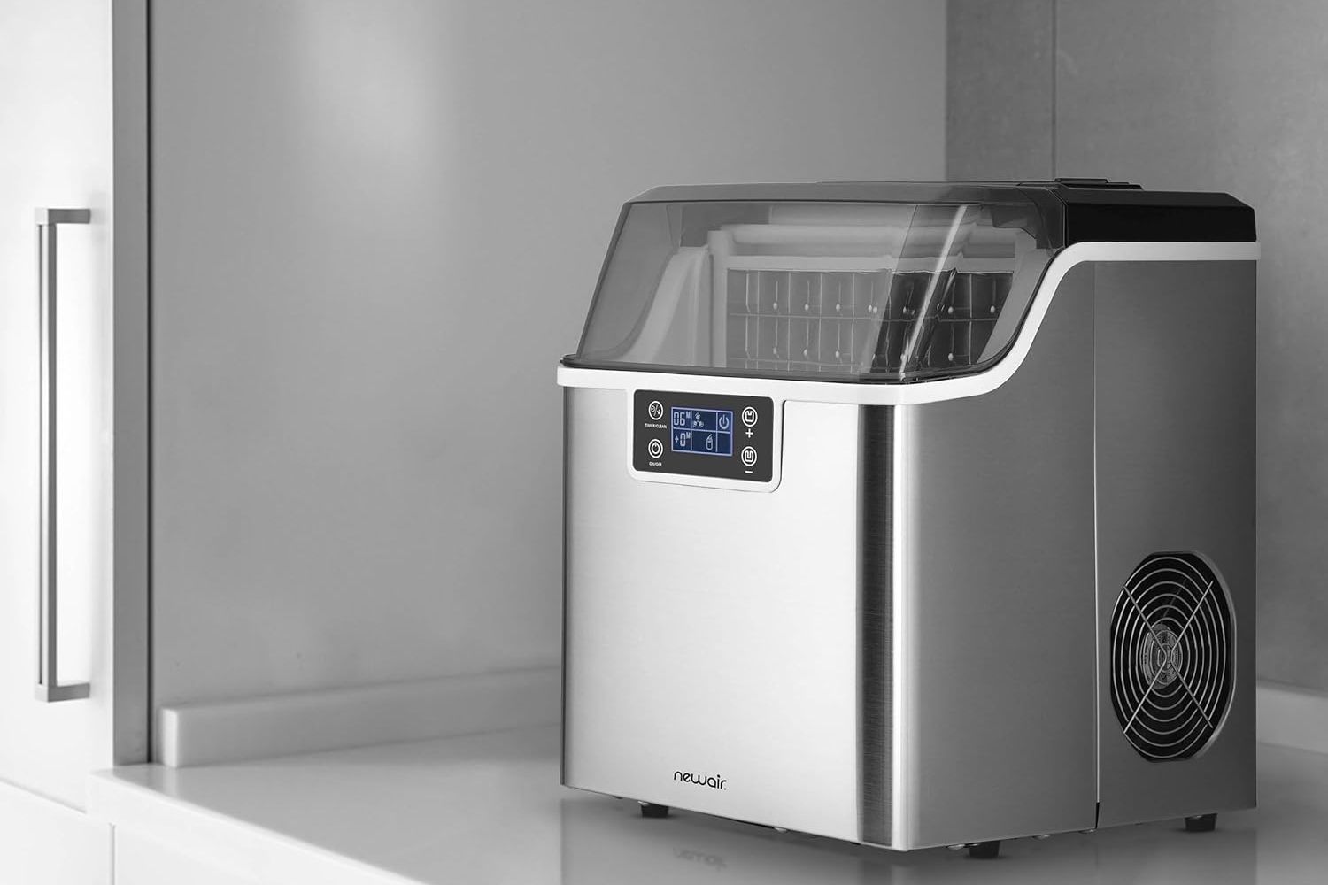 The Newair Countertop Clear Ice Maker on a kitchen counter next to a refrigerator.